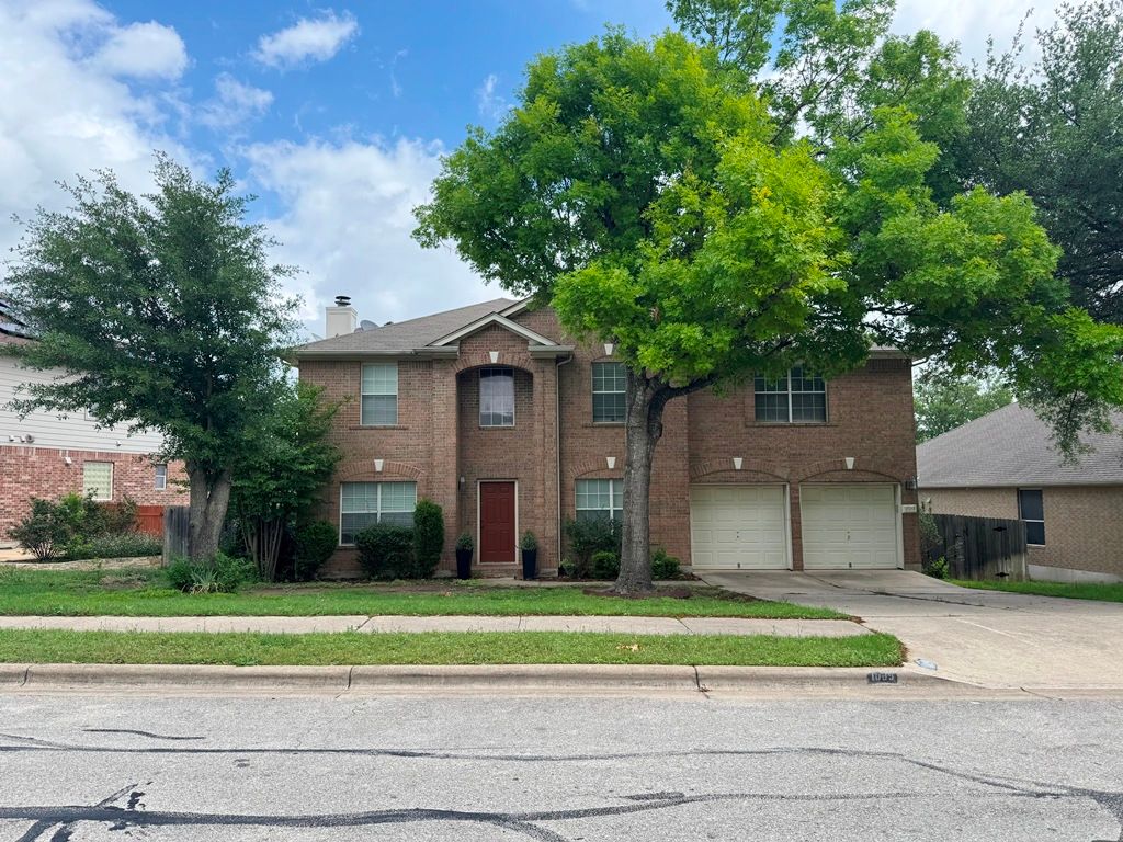 1009 Rutgers Drive Pflugerville, TX 78660 - Photo 2 of 3 Traditional home with driveway, a garage, brick siding, and a chimney