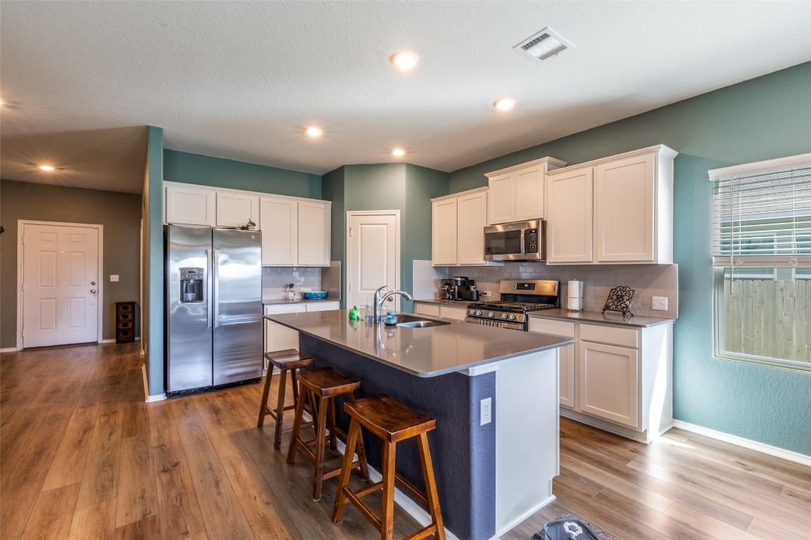 207 Otter Road Kyle, TX 78640 - Photo 10 of 26 a kitchen with stainless steel appliances granite countertop wooden cabinets a refrigerator a stove a sink and dishwasher with wooden floor