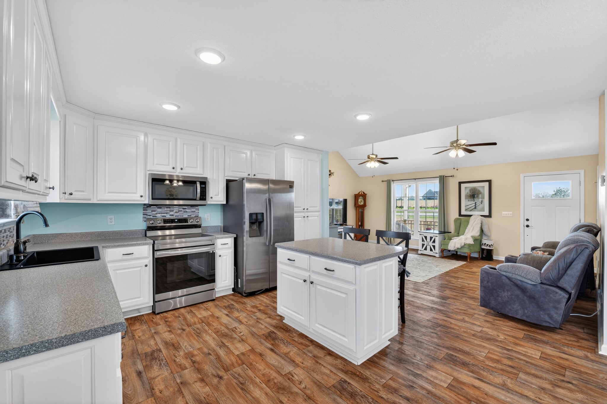 198 L Mitchell Road Flintville, TN 37335 - Photo 10 of 41 a kitchen with stainless steel appliances kitchen island granite countertop a stove a sink a refrigerator and white cabinets with wooden floor