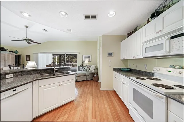 a kitchen with granite countertop a sink a counter space appliances and cabinets