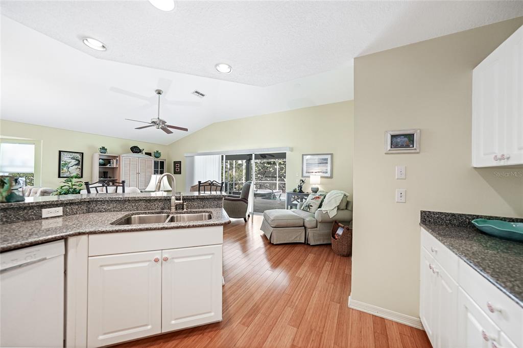 425 Islamorada Boulevard Punta Gorda, FL 33955 - Photo 10 of 44 a kitchen with a sink dishwasher a stove and white cabinets with wooden floor