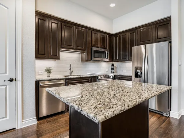 a kitchen with kitchen island granite countertop wooden cabinets and refrigerator