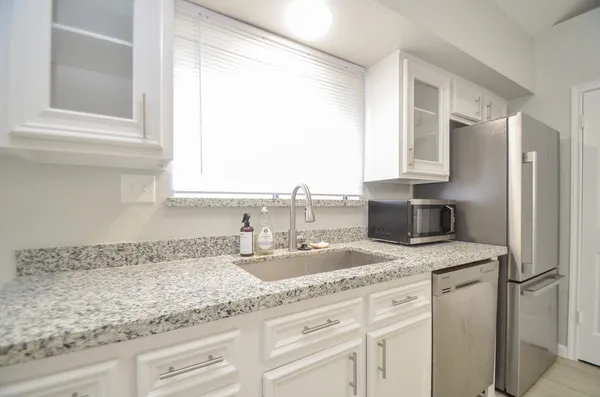 a kitchen with granite countertop a sink stainless steel appliances and cabinets