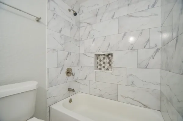 a white bath tub sitting next to a white toilet and vanity