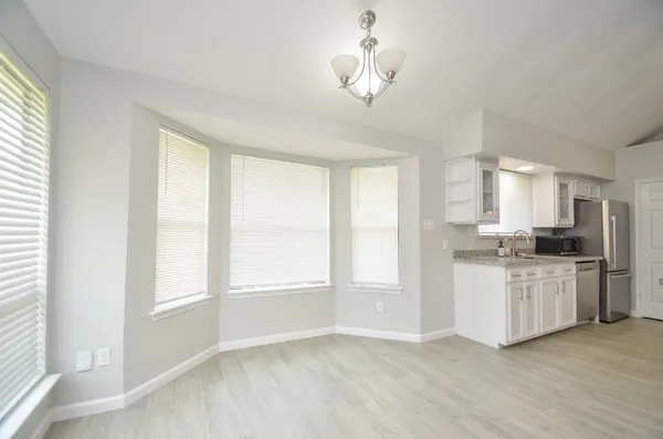 a kitchen with stainless steel appliances granite countertop a stove a sink dishwasher a refrigerator and white cabinets with wooden floor