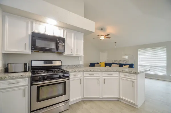 a kitchen with granite countertop a sink cabinets and stainless steel appliances