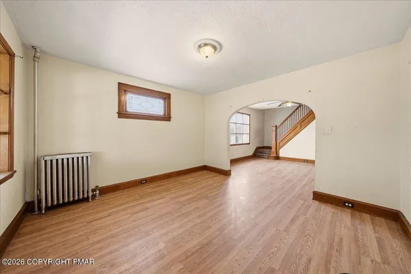 an empty room with wooden floor closet and windows
