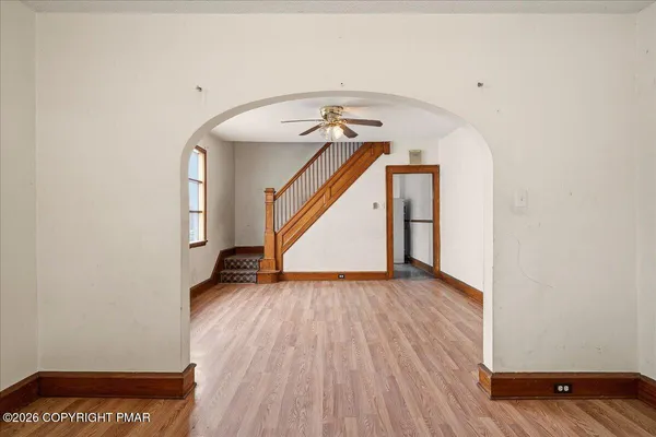 an empty room with wooden floor fan and windows