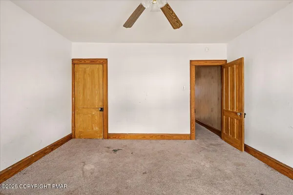 an empty room with windows and fan