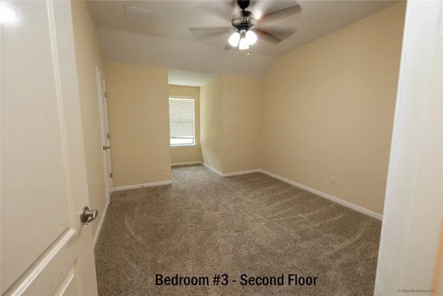 an empty room with a ceiling fan and carpet