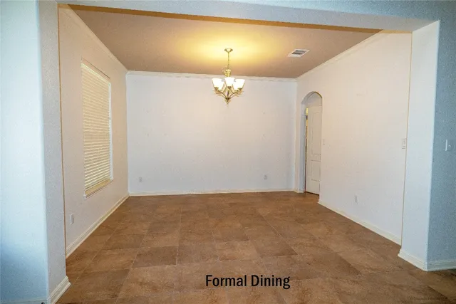 an empty room with a chandelier fan and windows