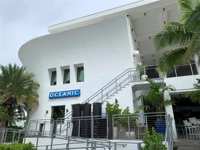 a front view of a house with glass windows and palm tree
