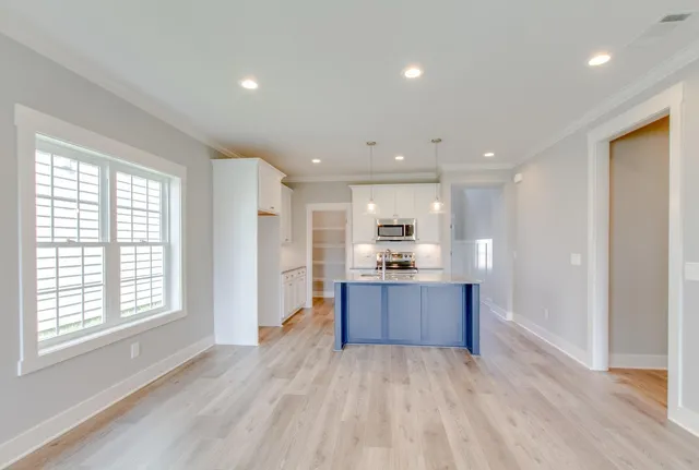 a view of kitchen with kitchen island wooden floor center island and stainless steel appliances