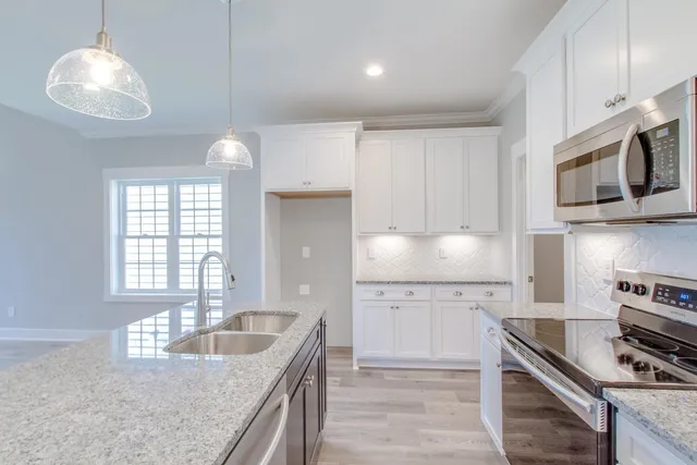 a kitchen with stainless steel appliances granite countertop a sink a stove and a refrigerator