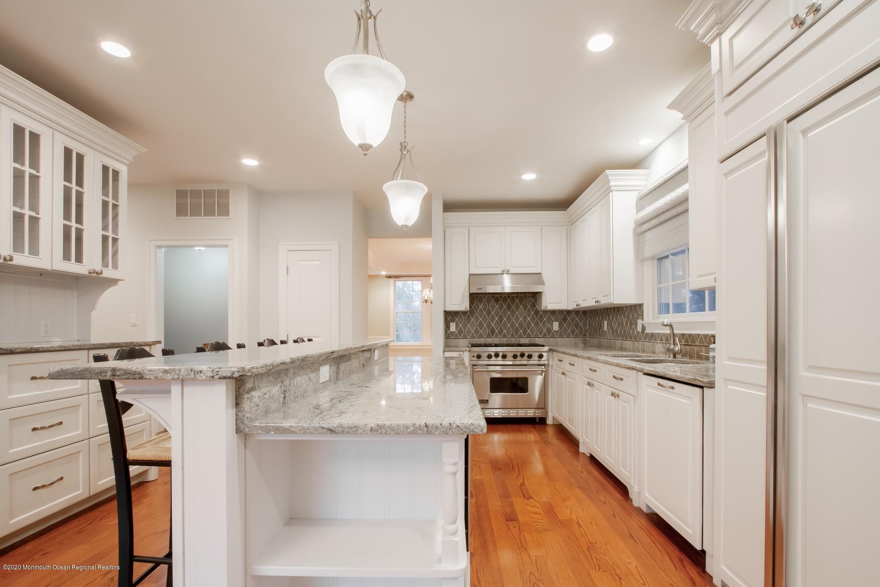 63 River Road Rumson, NJ 07760 - Photo 4 of 37 a kitchen with stainless steel appliances granite countertop a stove top oven a sink dishwasher a dining table and chairs with wooden floor