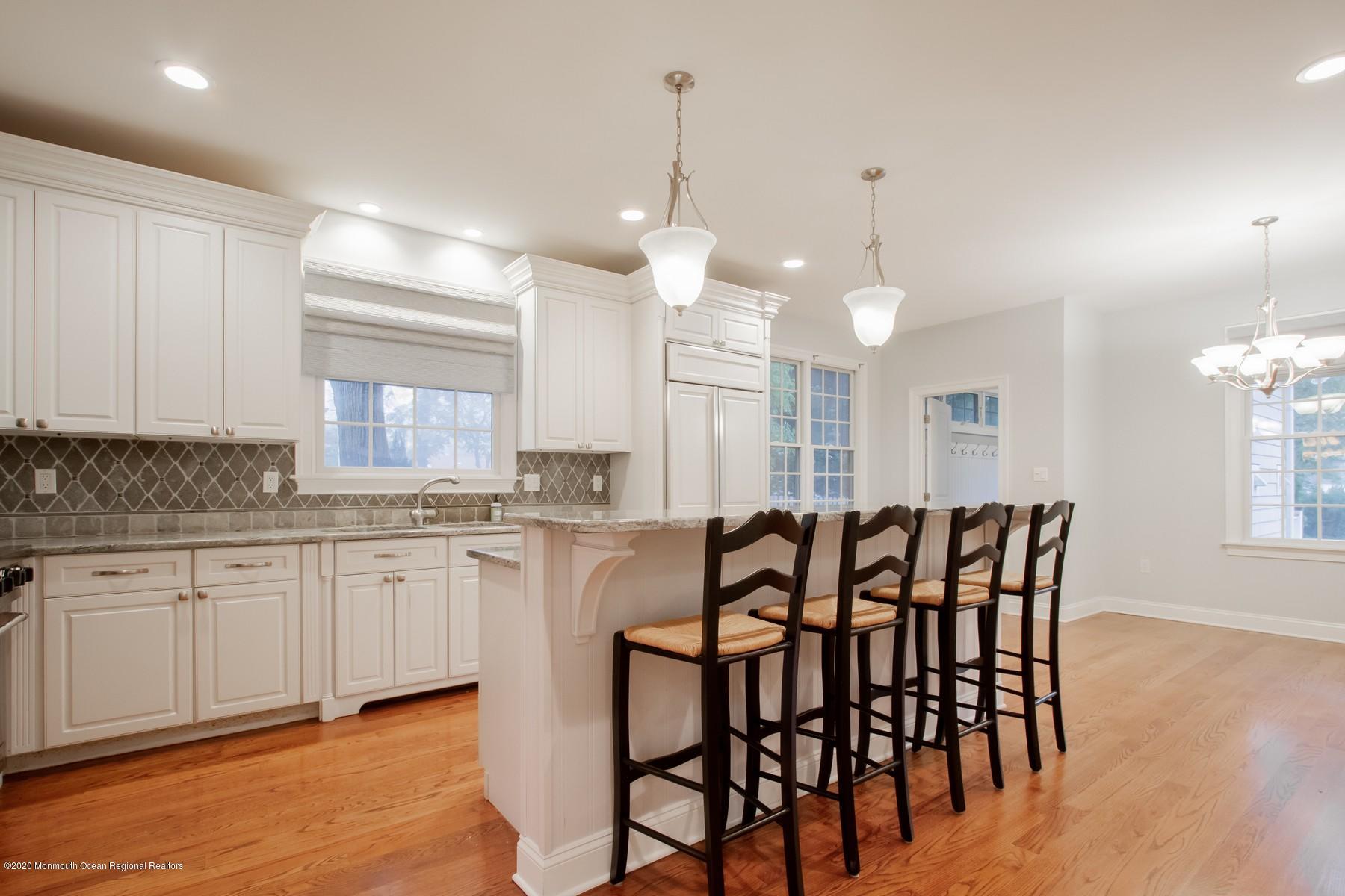 63 River Road Rumson, NJ 07760 - Photo 8 of 37 a large kitchen with granite countertop a table chairs sink and cabinets