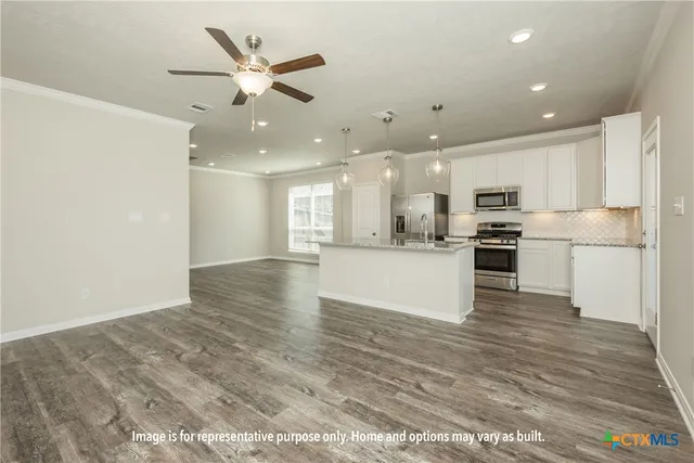 a view of kitchen with kitchen island white cabinets and refrigerator