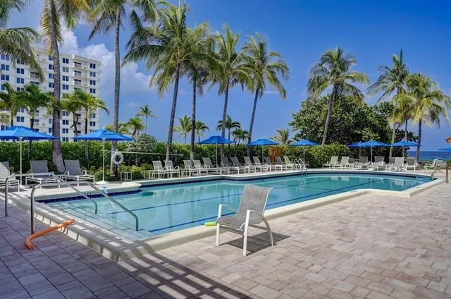 a view of a swimming pool with a chair and palm trees