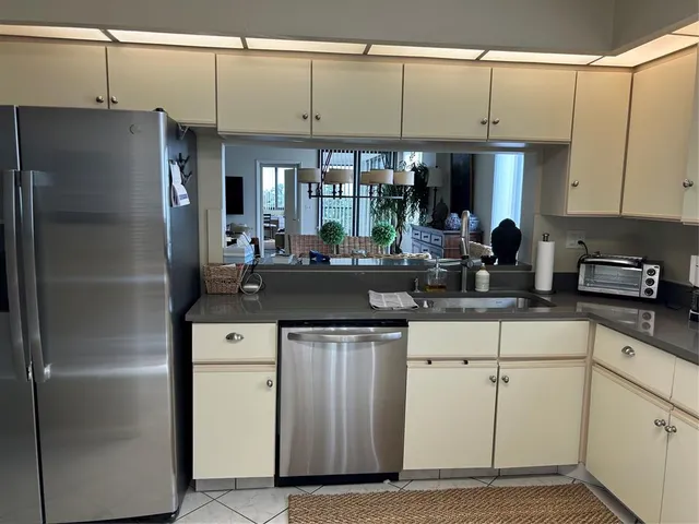 a kitchen with stainless steel appliances granite countertop a refrigerator a sink and white cabinets