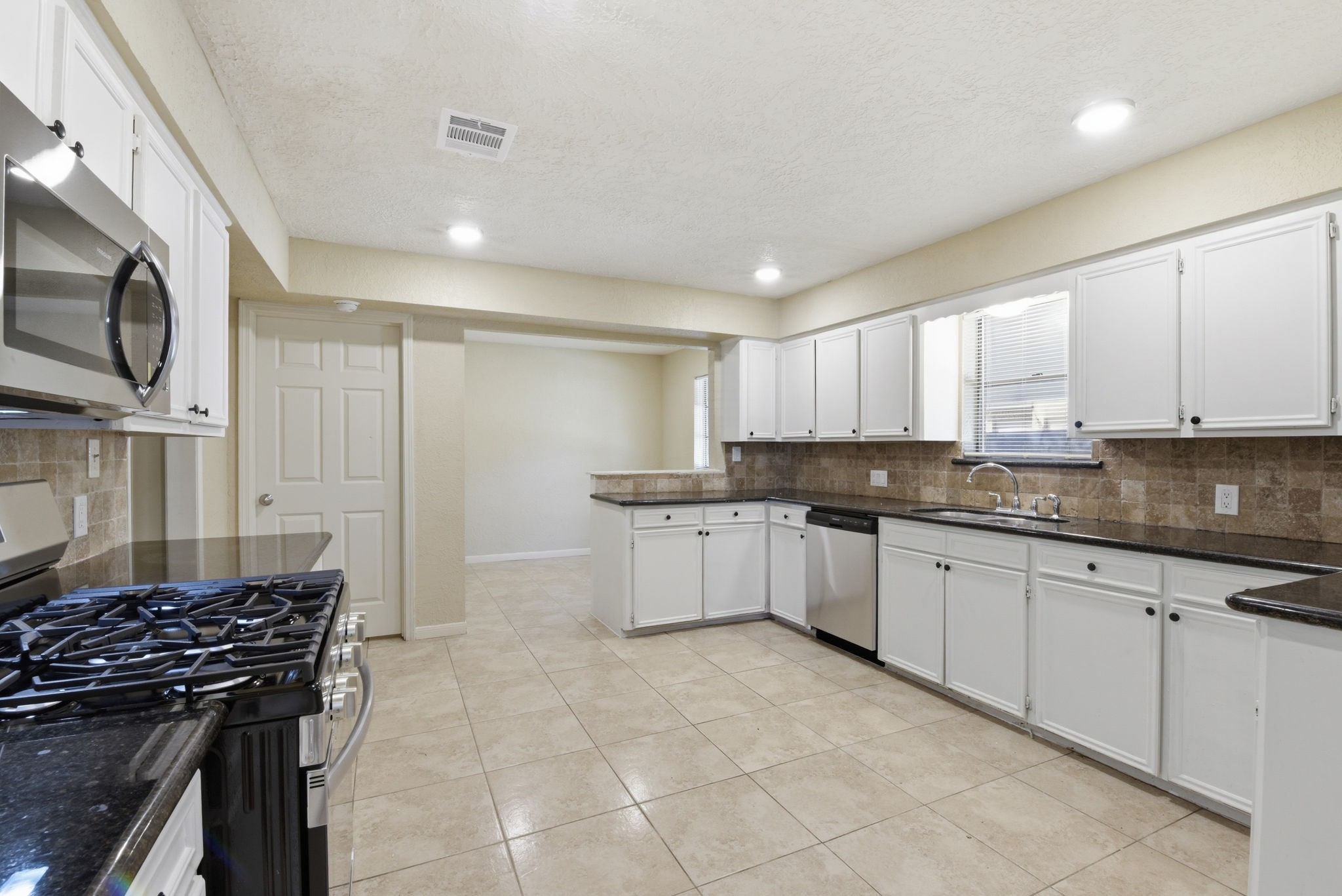 9052 Zapata Way Willis, TX 77378 - Photo 18 of 45 a kitchen with granite countertop a stove sink and cabinets
