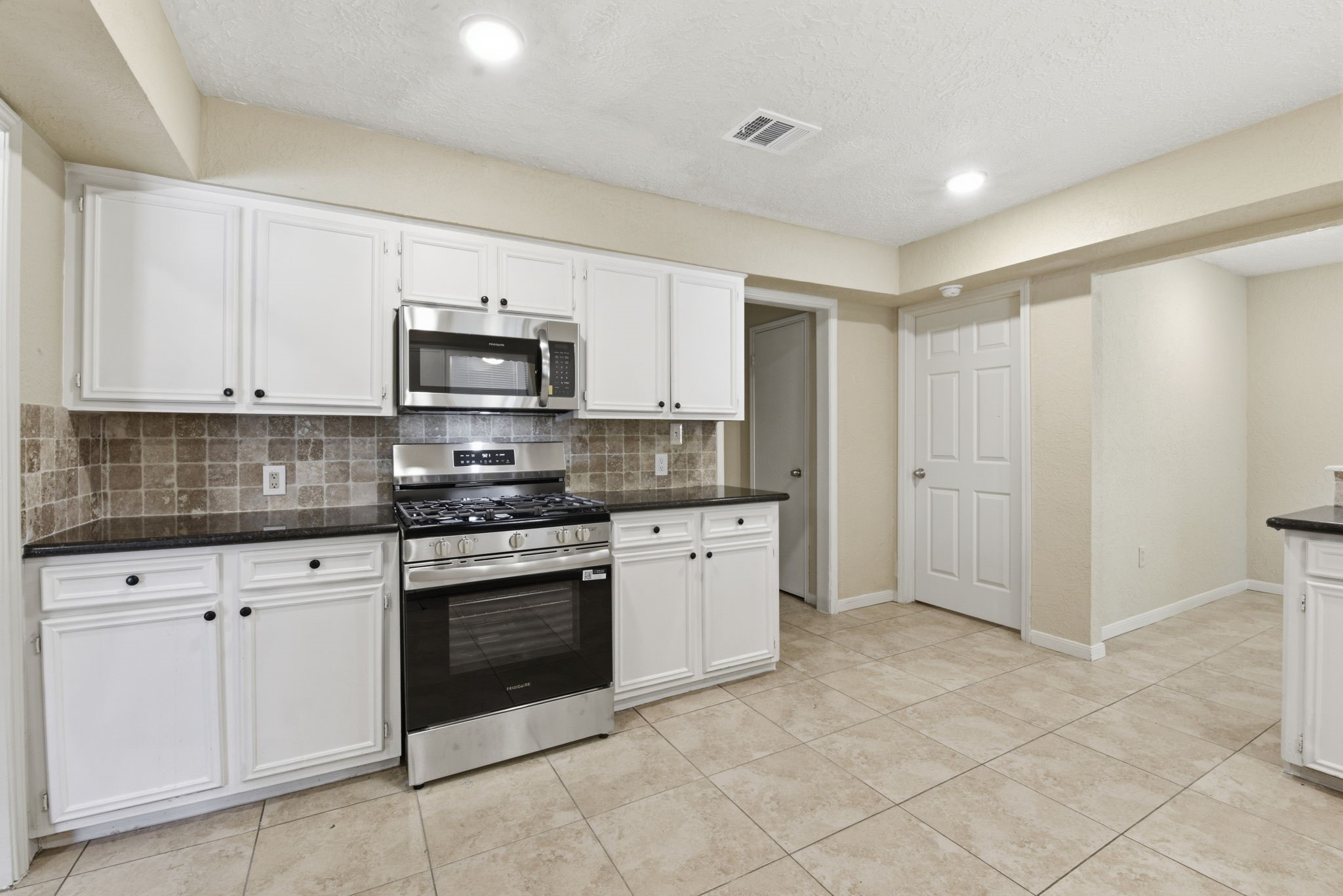 9052 Zapata Way Willis, TX 77378 - Photo 20 of 45 a kitchen with granite countertop white cabinets and stainless steel appliances