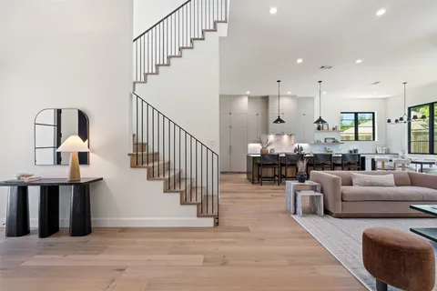 a living room with furniture large windows and wooden floor