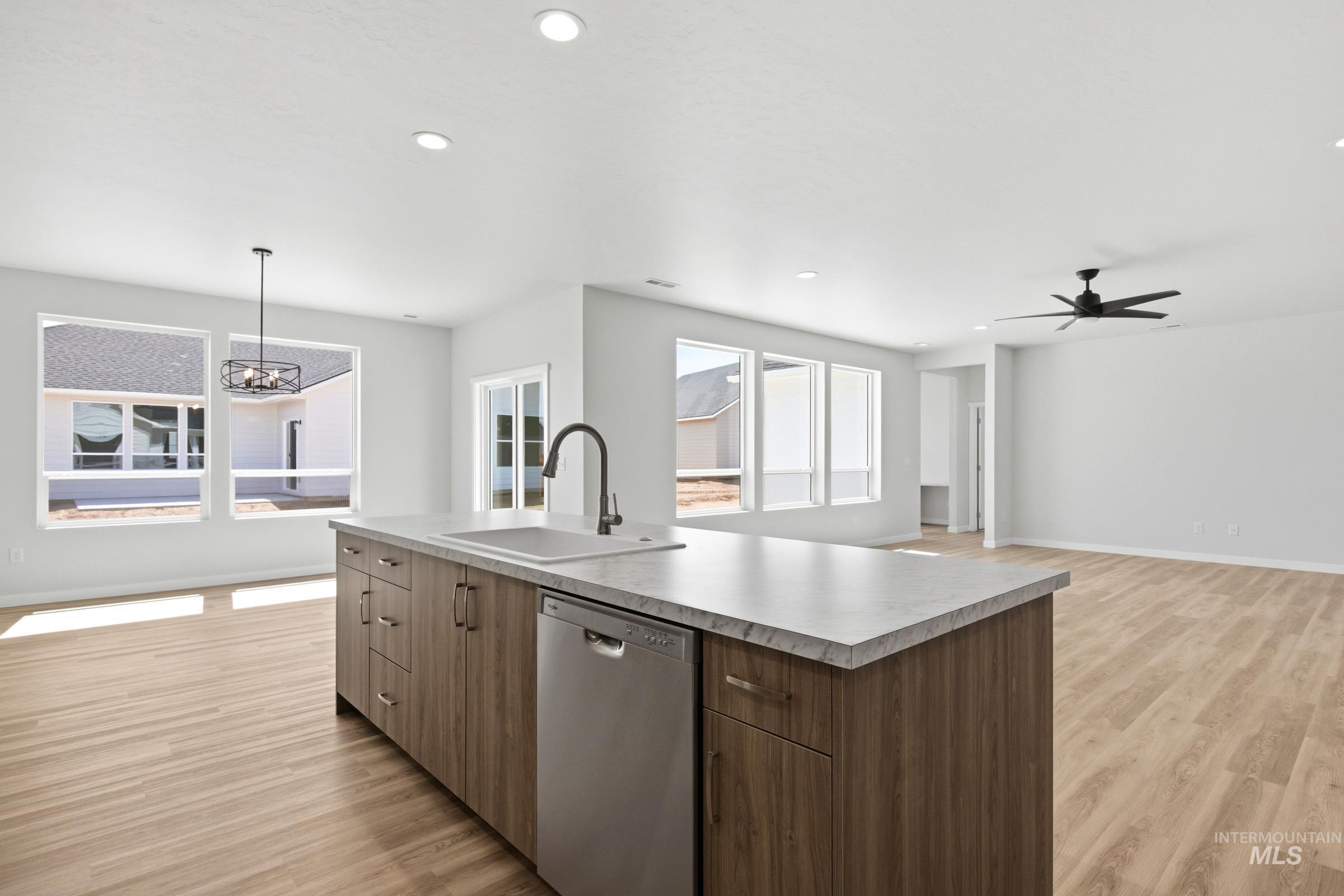 13649 Inman Court Caldwell, ID 83607 - Photo 9 of 22 Kitchen island featuring a single-basin sink with a gooseneck faucet, wood-finish cabinetry, and stainless steel dishwasher
