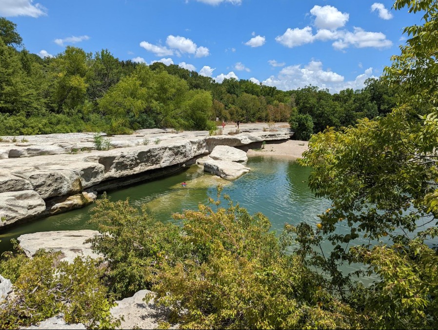 2702 Sebring Circle Austin, TX 78747 - Photo 30 of 35 Natural rock ledges frame a serene waterway surrounded by lush green trees.