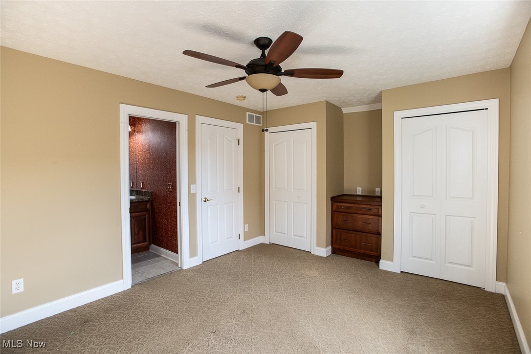 630 Rundle Street Lagrange, OH 44050 - Photo 39 of 49 Unfurnished bedroom featuring a textured ceiling, two closets, ensuite bath, a ceiling fan, and light carpet