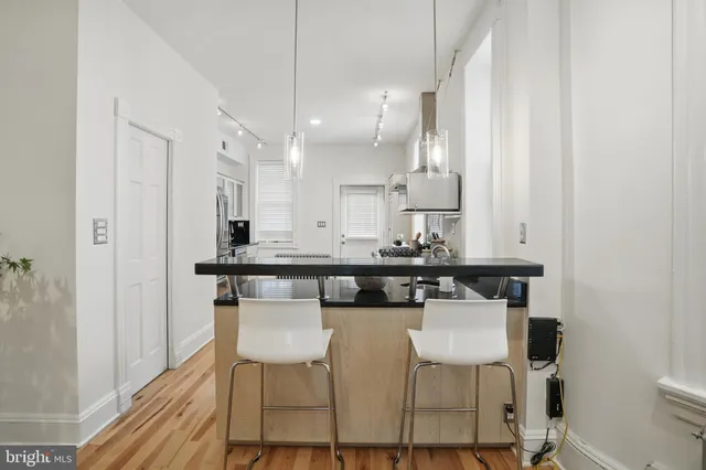 a kitchen with stainless steel appliances kitchen island granite countertop a table chairs a sink and white cabinets