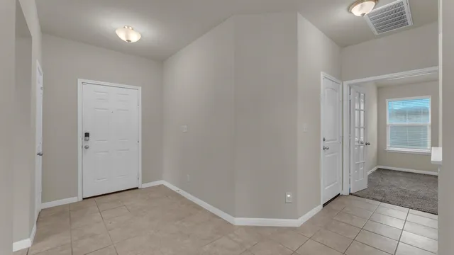 an empty room with mirror and a bathroom