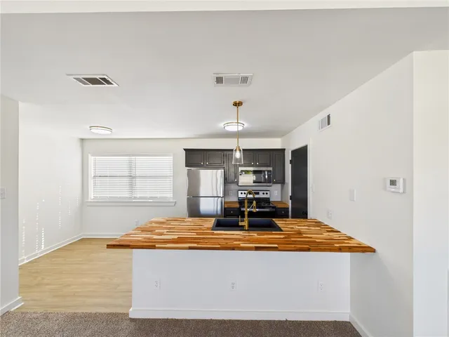 a view of kitchen with kitchen island stainless steel appliances a sink and wooden floor