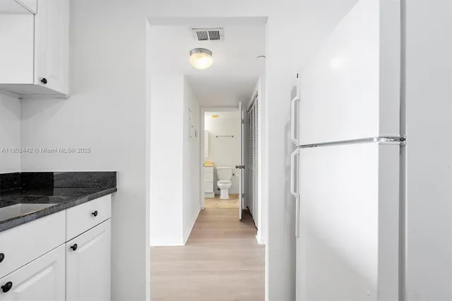 a kitchen with granite countertop white cabinets and white appliances
