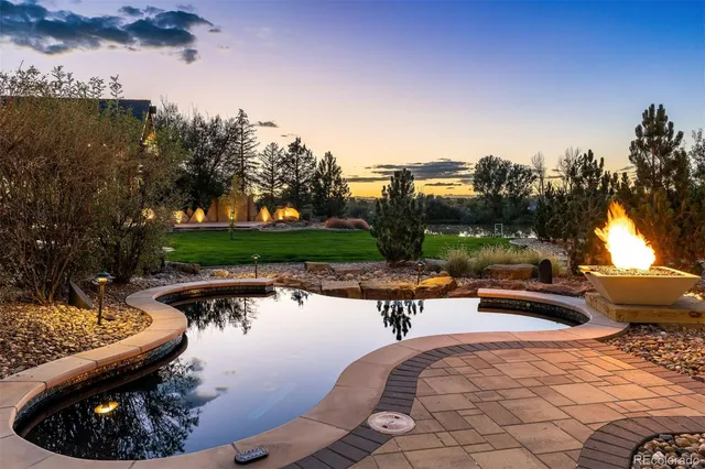 a view of a swimming pool and lounge chairs in back yard of the house