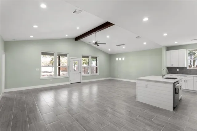 a large kitchen with kitchen island a stove a sink a refrigerator and white cabinets with wooden floor