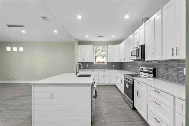 a view of kitchen with kitchen island granite countertop a stove top oven a sink and a refrigerator with wooden floor