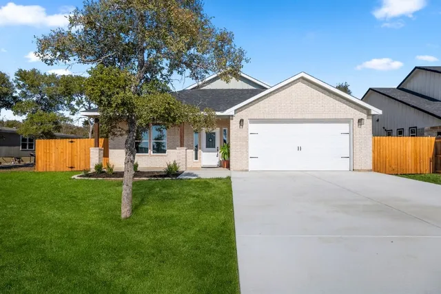 a view of a white house with a yard and a large tree