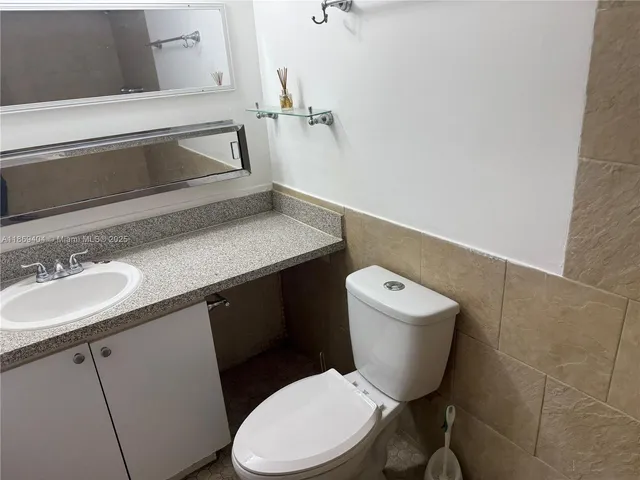 a bathroom with a granite countertop toilet sink mirror and vanity