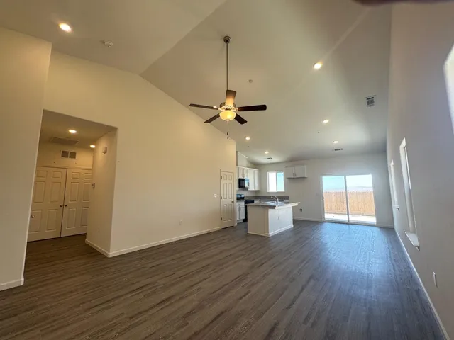 a view of a room with wooden floor and a ceiling fan