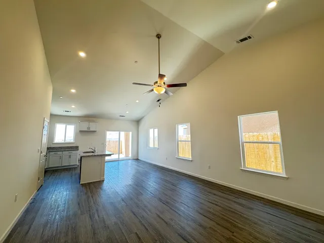 a view of a kitchen and an empty room with a window
