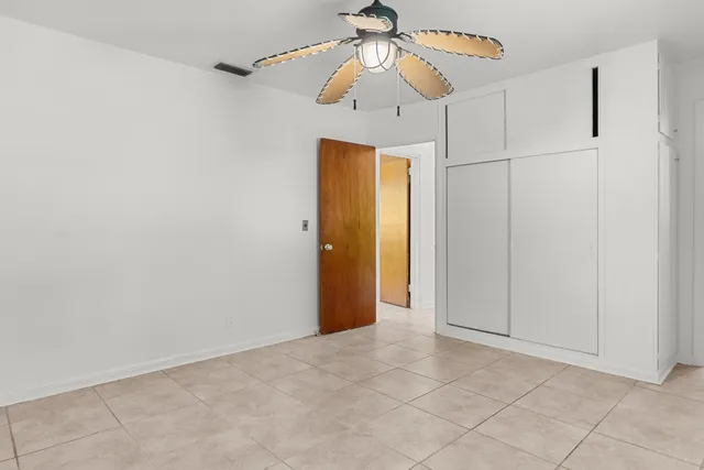 an empty room with closet and a chandelier fan