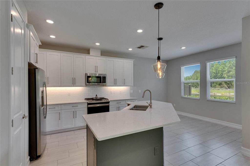 4899 Isola Court Wesley Chapel, FL 33543 - Photo 32 of 86 a kitchen with kitchen island a sink stainless steel appliances and window