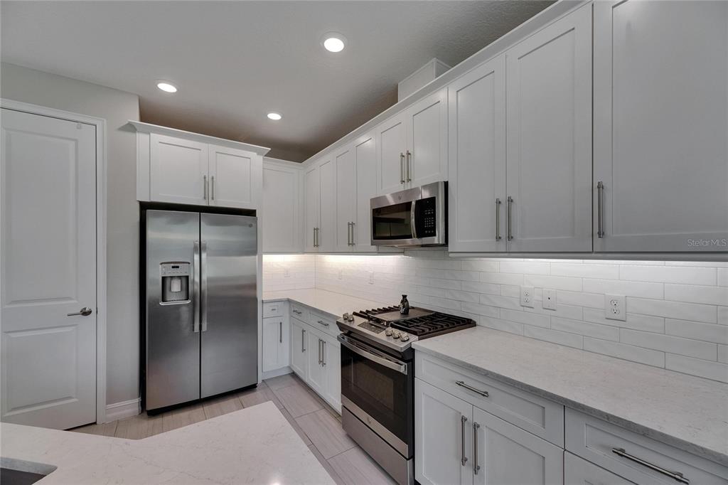 4899 Isola Court Wesley Chapel, FL 33543 - Photo 34 of 86 a kitchen with stainless steel appliances granite countertop a refrigerator and a stove top oven