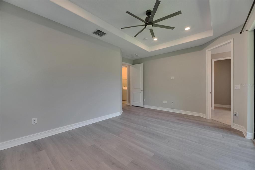 4899 Isola Court Wesley Chapel, FL 33543 - Photo 59 of 86 an empty room with wooden floor and a ceiling fan