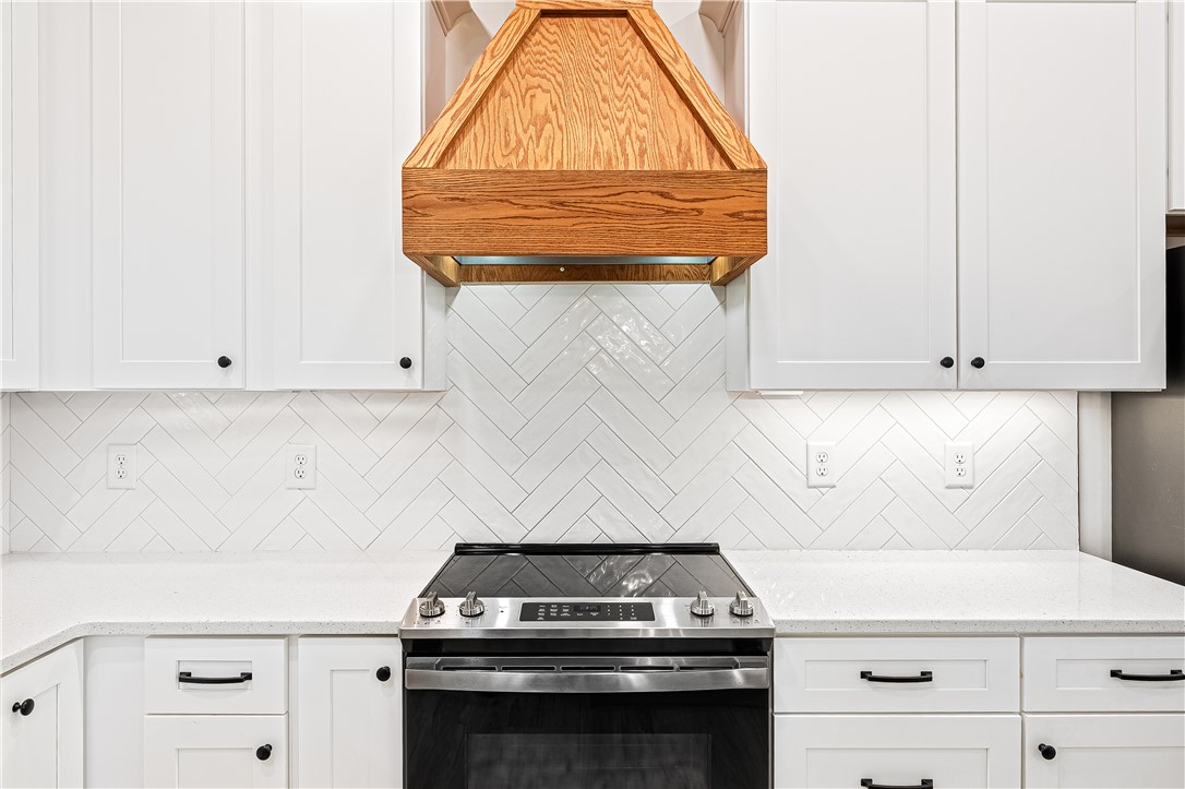 516 Winding Way Hartwell, GA 30643 - Photo 12 of 50 White cabinetry, solid surface countertops, and a striking herringbone tile backsplash elevate this inviting kitchen.