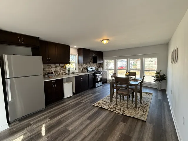 a kitchen with a dining table chairs refrigerator and cabinets