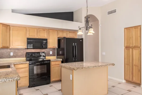 a kitchen with kitchen island granite countertop a stove a sink and a chandelier