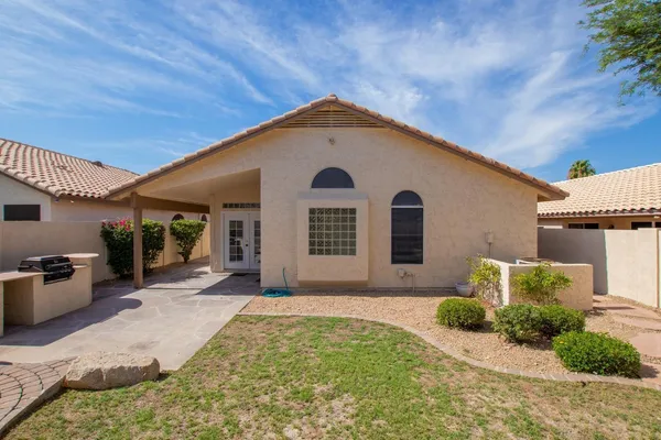 a backyard of a house with table and chairs plants and large tree