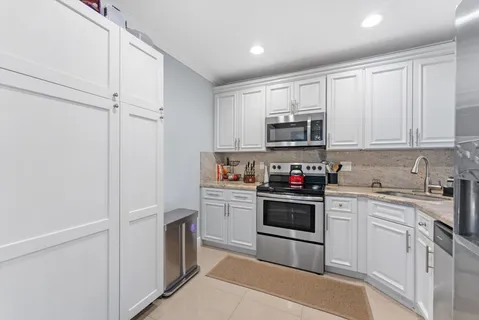a kitchen with cabinets stainless steel appliances and sink