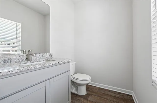 a bathroom with a granite countertop toilet a sink and a mirror